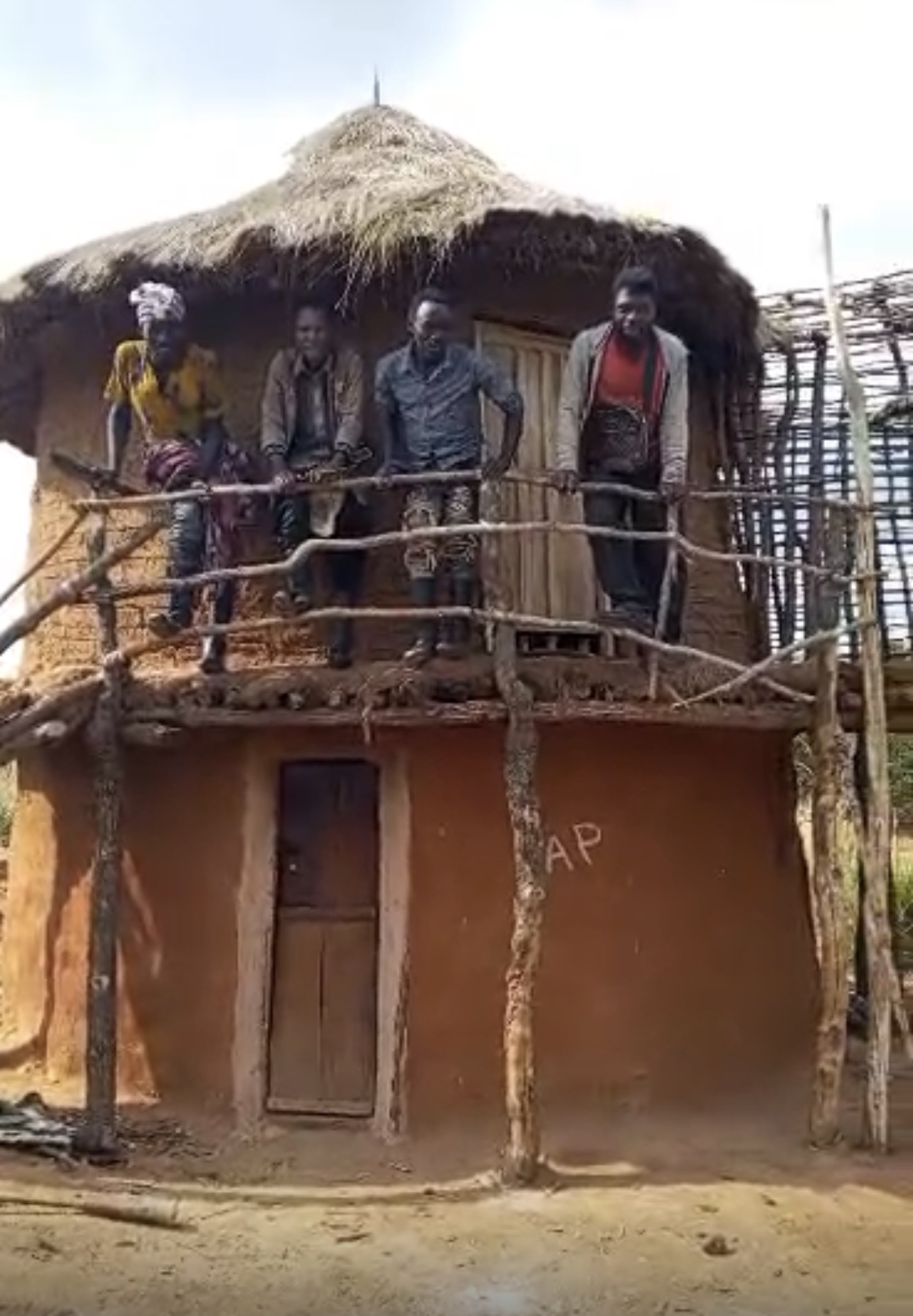 Community members outside a rural home, representing communities at the heart of OLIFE's vision